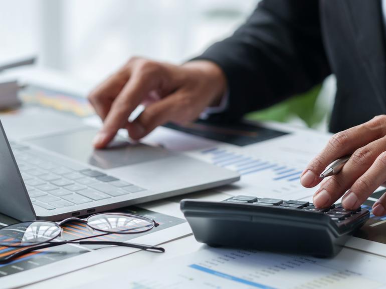 Image of person typing on laptop and using a calculator