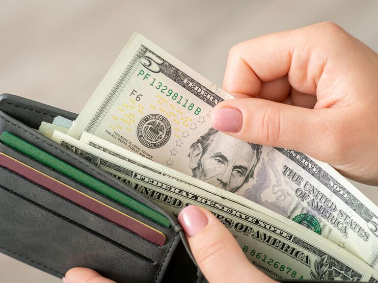 Woman pulling five dollar U.S. bill out of wallet