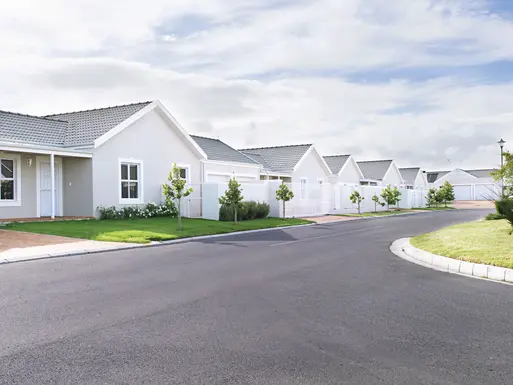 build-to-rent property with white houses and fences on a road with grass