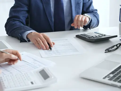 Real estate investors analyzing financing documents with a pen and calculator