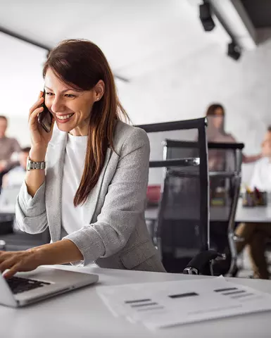 Professional woman talking on the phone and typing on laptop